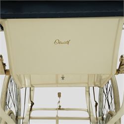 Mid-20th century Osnath pram, the cream painted metal body with navy fabric hood and apron, cream vinyl lined interior fitted with patterned mattress, raised on sprung metal supports with spoked wheels and white rubber tyres