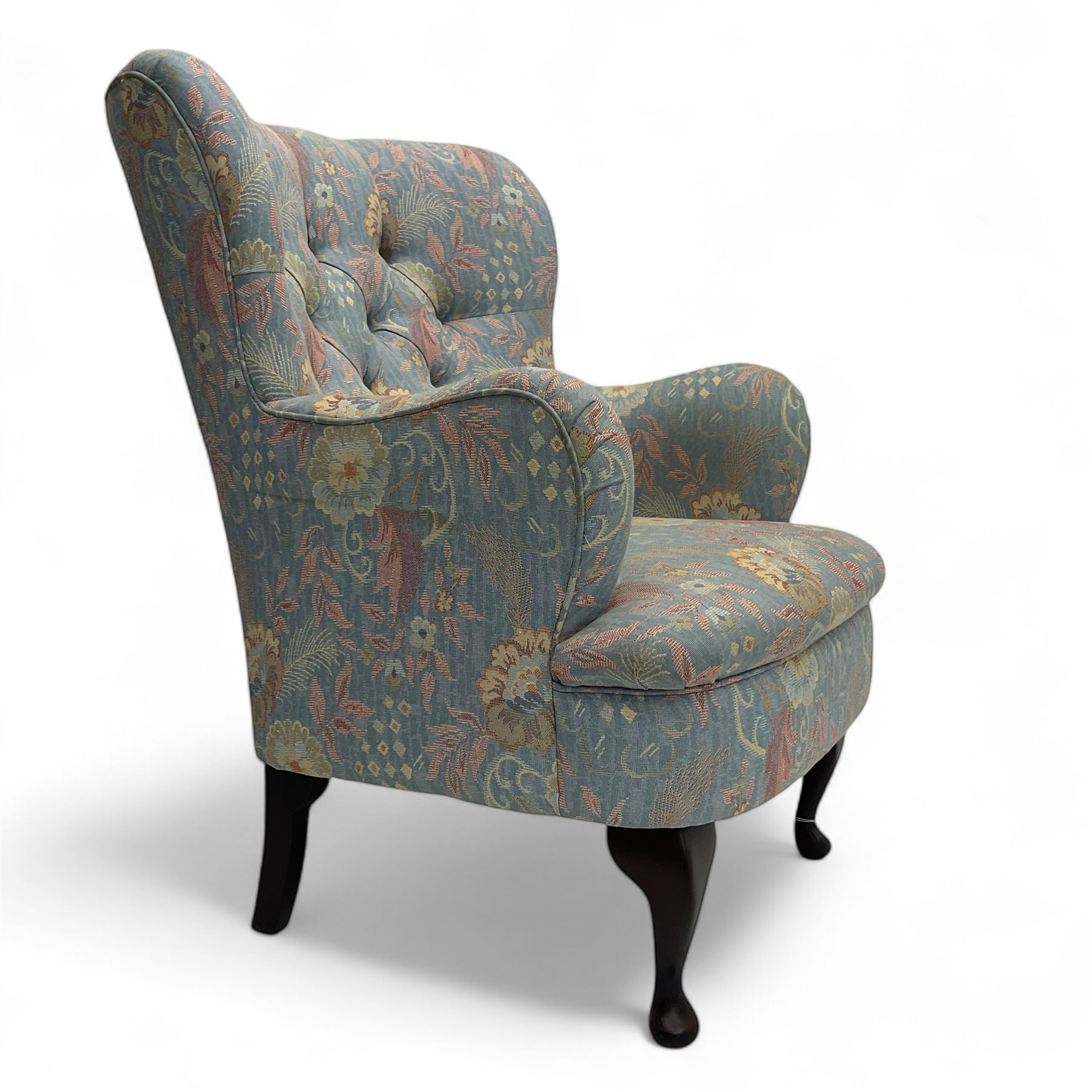 Mid-20th century wingback armchair, upholstered in soft blue floral patterned fabric with button-tufted backrest and curved arms and raised on cabriole supports