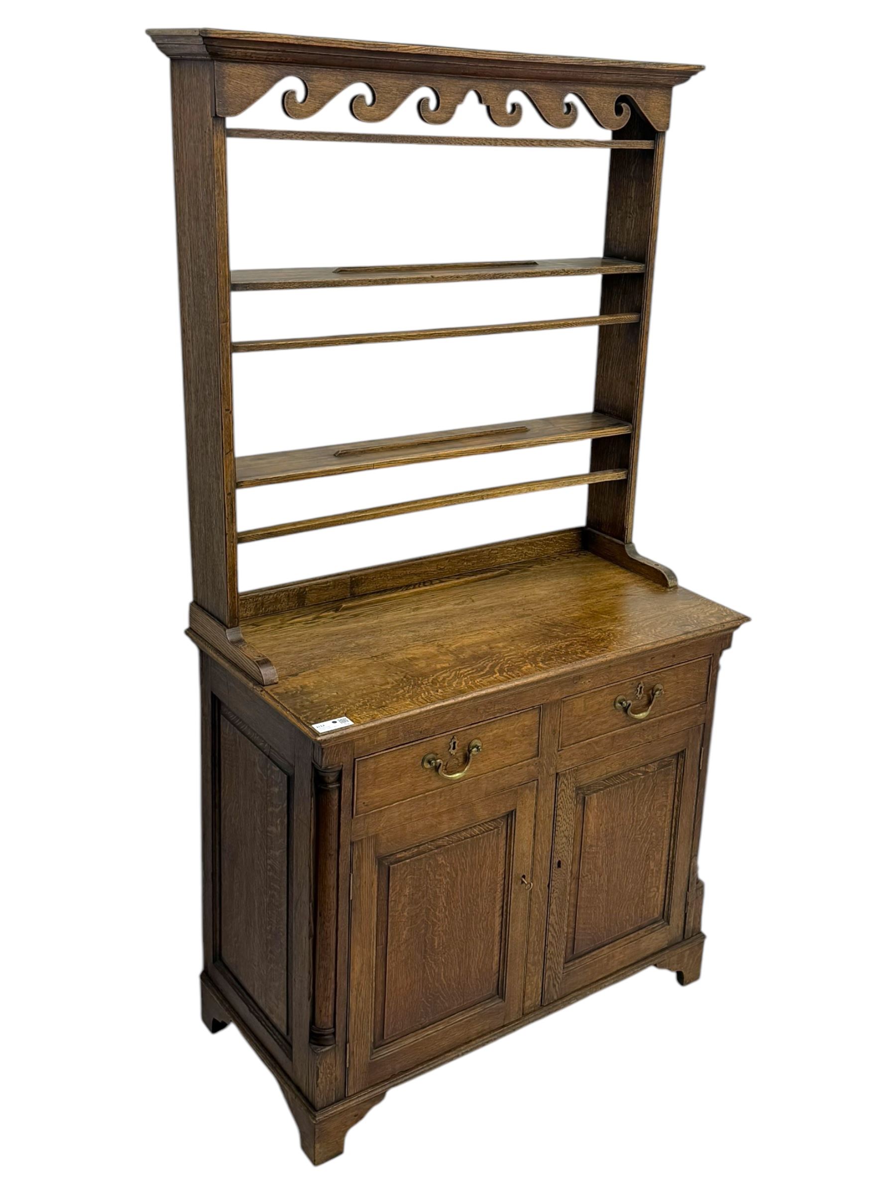 19th century and later oak dresser, moulding cornice a pierced and shaped frieze, over two open plate shelves above a base fitted with two drawers with brass swan neck handles, over panelled twin cupboard with single shelf, cantered corners on bracket feet