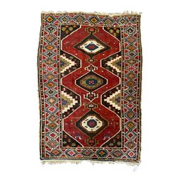 Anatolian Turkish red ground rug, decorated with three central lozenges, the multi-colour guarded border with repeating geometric shapes