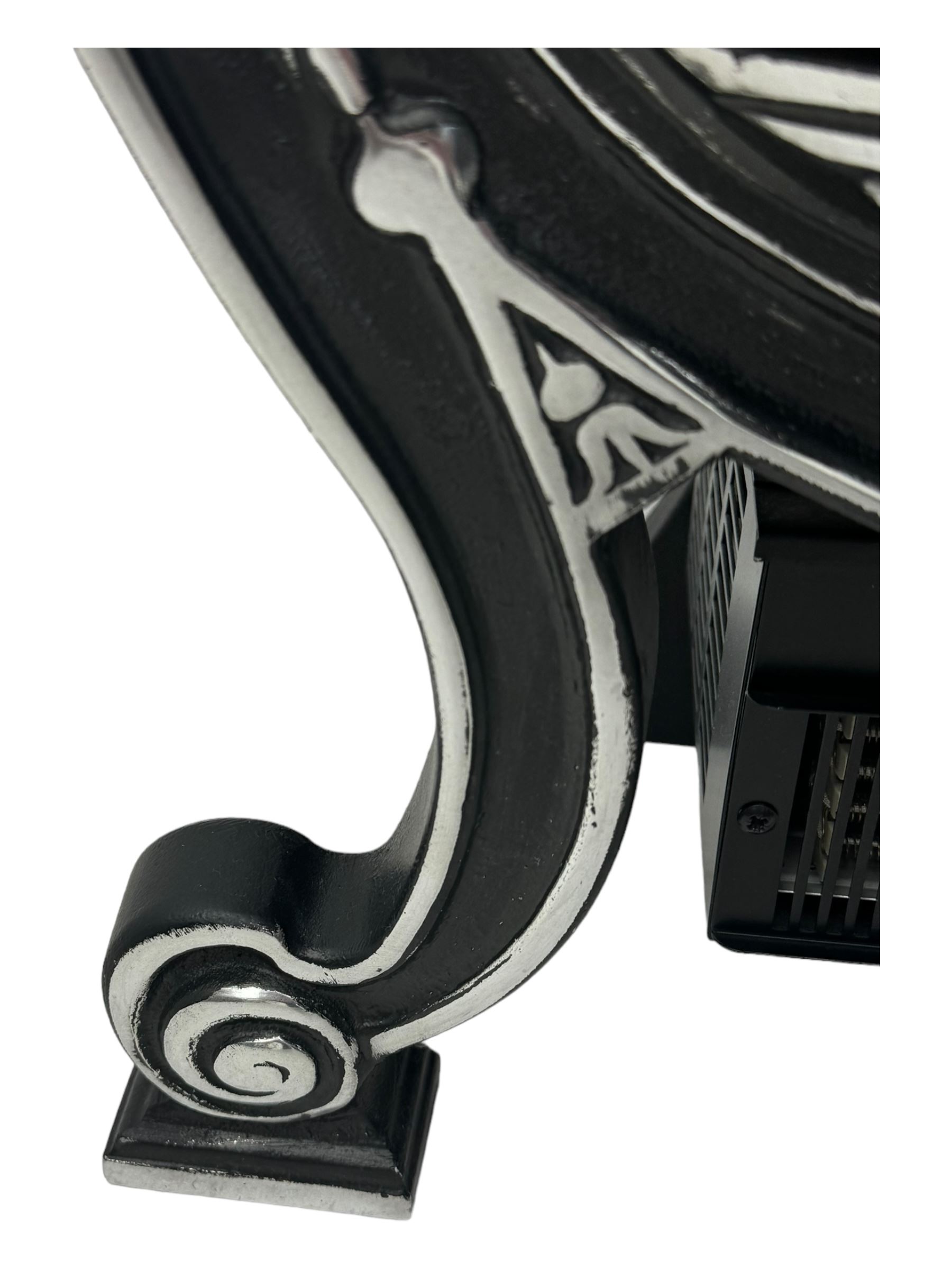 Stained glass and cast iron electric fireplace, arched top with decorative finials, stained glass front panel with floral motifs, flanked by cast iron scrolls, raised on scroll supports