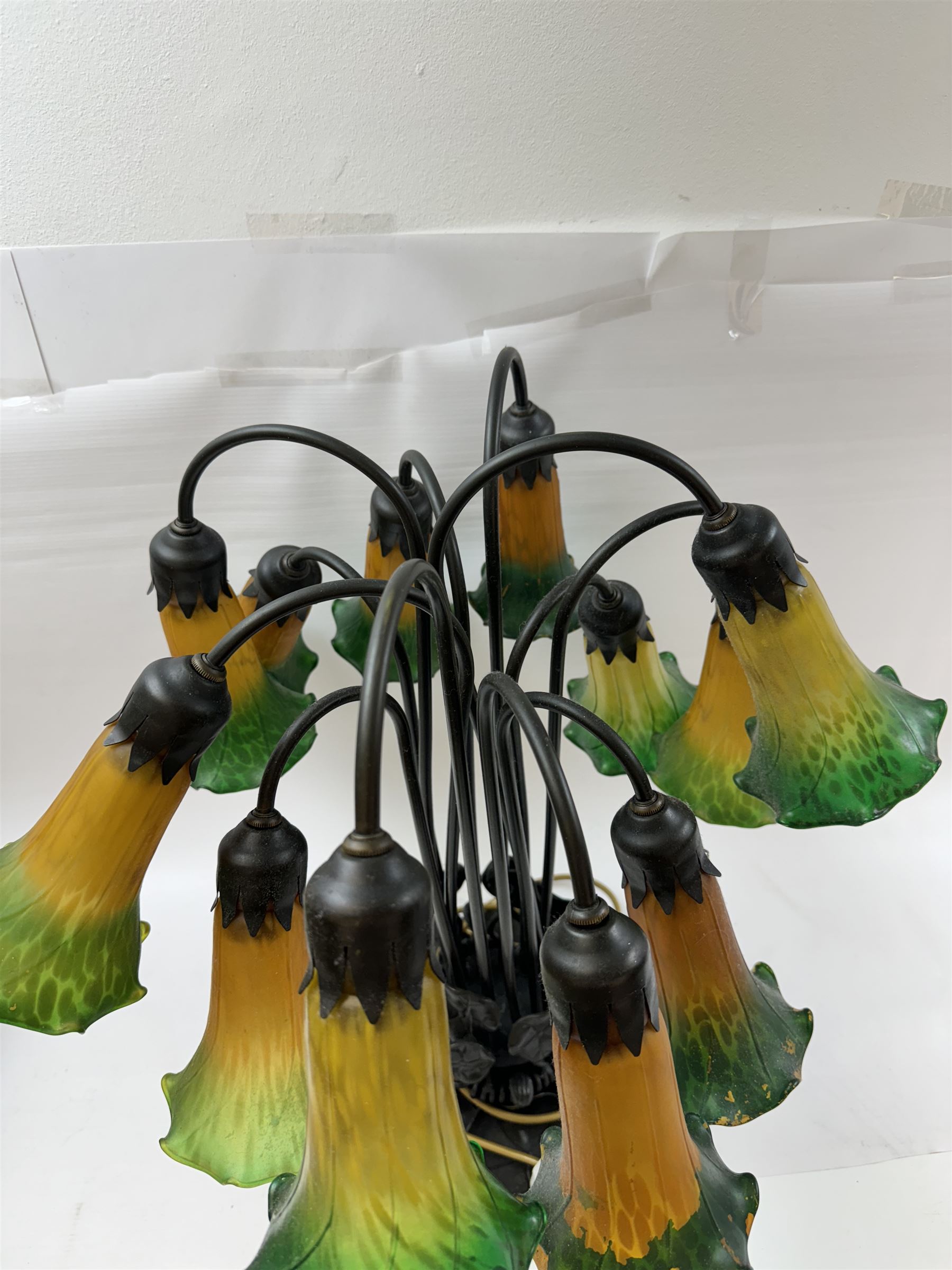 Art Nouveau Tiffany style table lamp, the bronzed base modelled as lily pads leading to tendrils and twelve branches supporting green and yellow glass lily flower shades, H53cm
