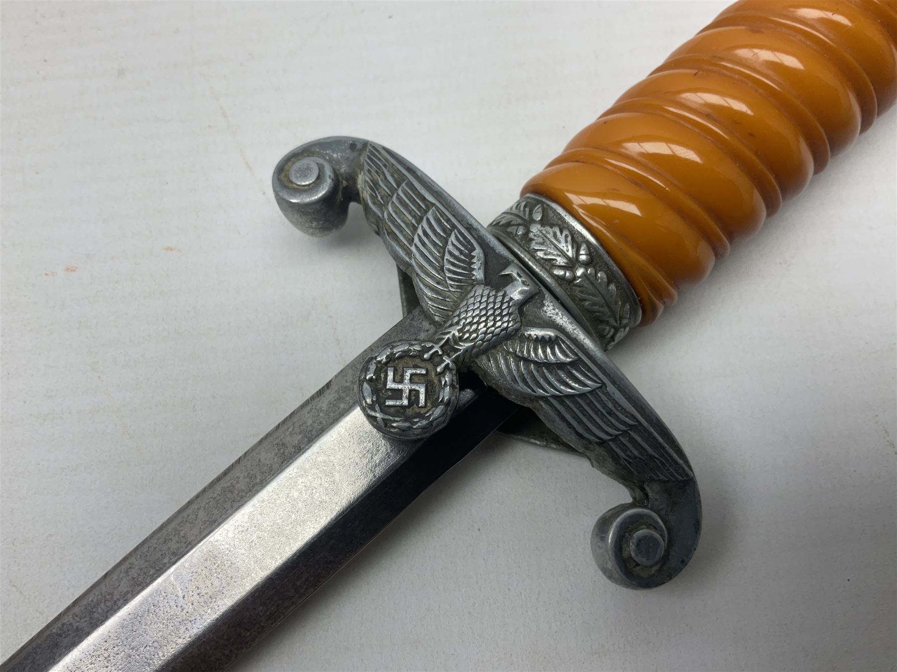 Late WW2 German Army Officers dress dagger, with unmarked 25cm double edged steel blade, orange celluloid grip, pommel and ferrule with oakleaves relief and cross guard with eagle; in original beaded scabbard with two hanging rings L39.5cm overall