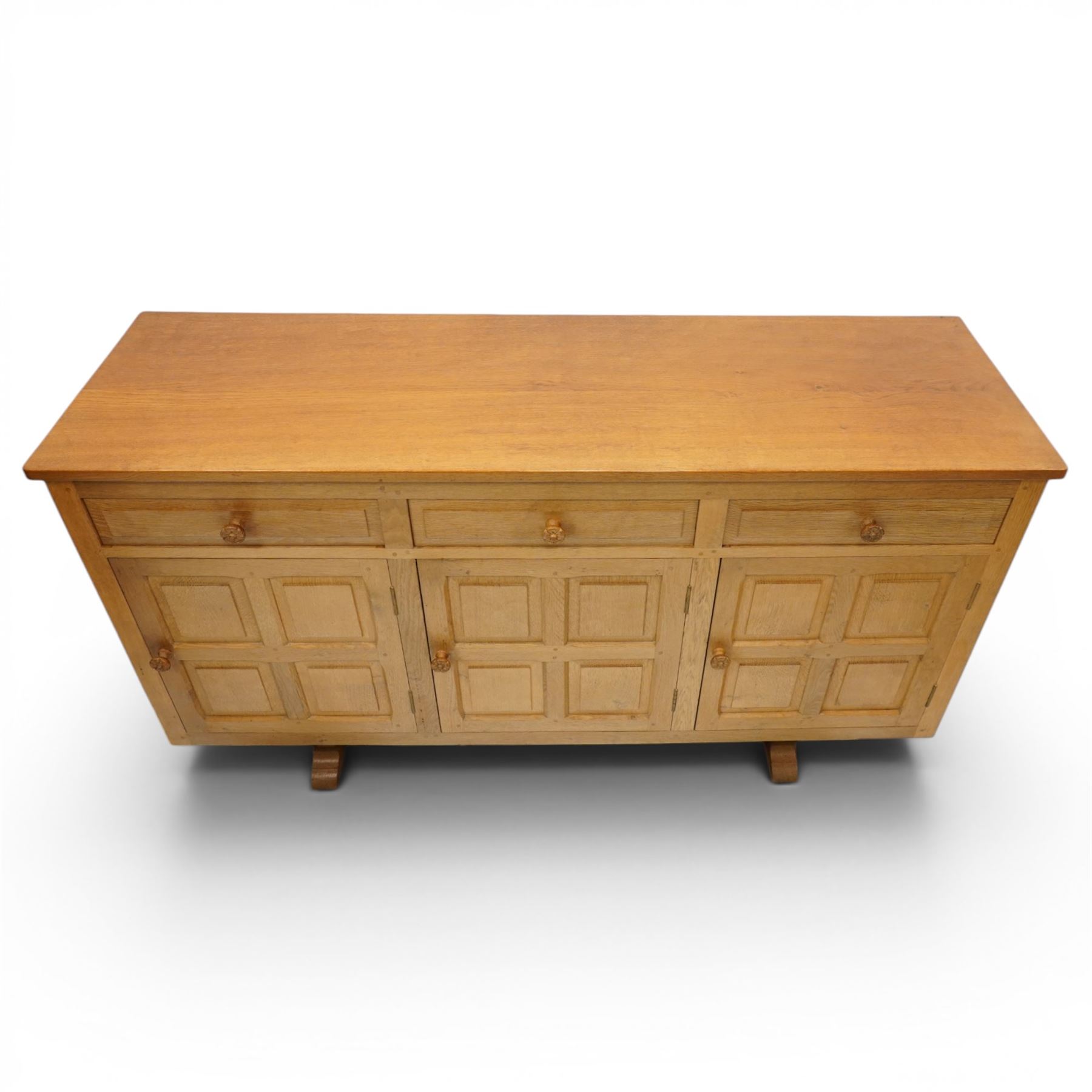 Beaverman - 1980s adzed oak sideboard raised on a trestle base, three drawers over three cupboards with Yorkshire Rose carved handles, fielded panelled sides and front, with carved Beaver, by Colin Almack of Sutton near Thirsk