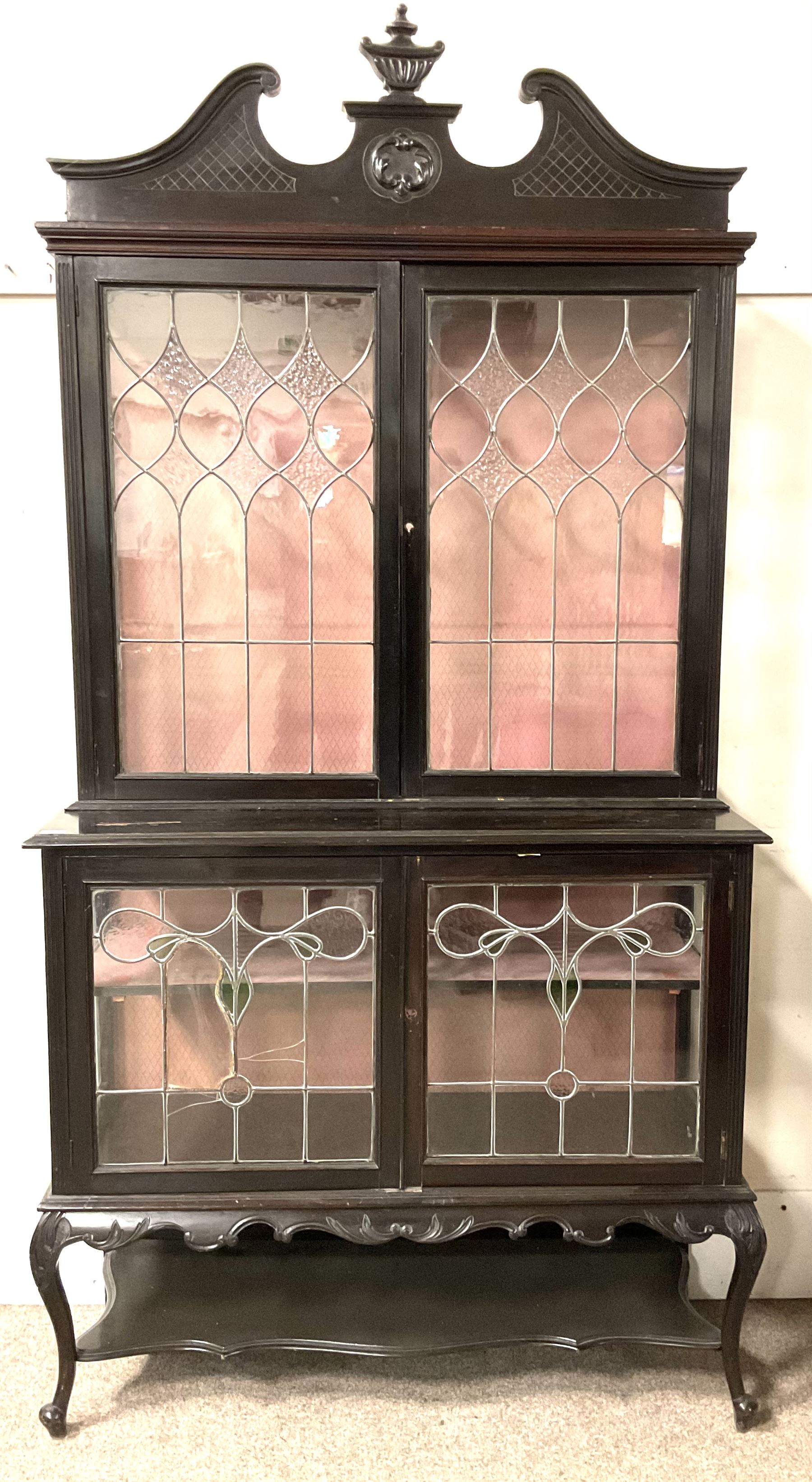 Late 19th century mahogany Empire style display cabinet, swan neck pediment and carved urn finial over two lead glazed doors enclosing two shelves, two glazed doors under, raised on cabriole front supports