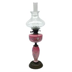 Pink opaline glass oil lamp of baluster form made with hand painted floral decoration upon a circular plinth, H80cm