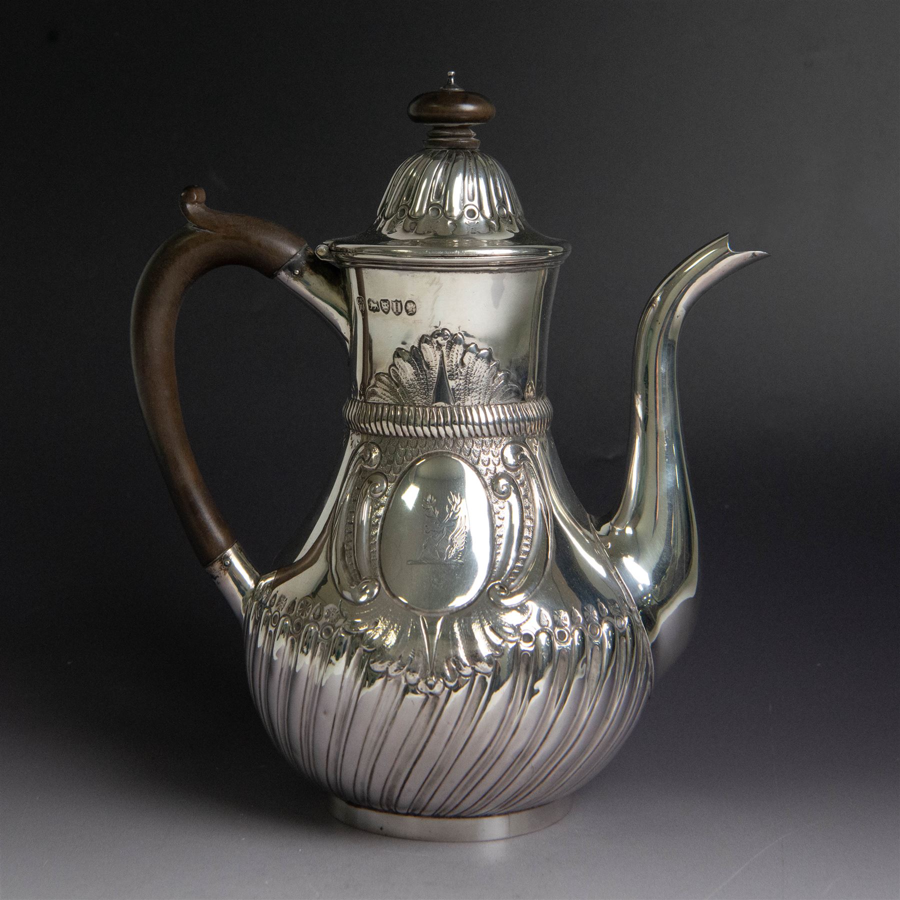 Victorian silver coffee pot, of part fluted baluster form, with central oval cartouche engraved with peryton crest, bordered by C scrolls and chased scales, with impressed acorns, stars and leaves throughout, with wooden handle and finial to domed hinged cover, hallmarked Charles Stuart Harris, London 1883, H23cm