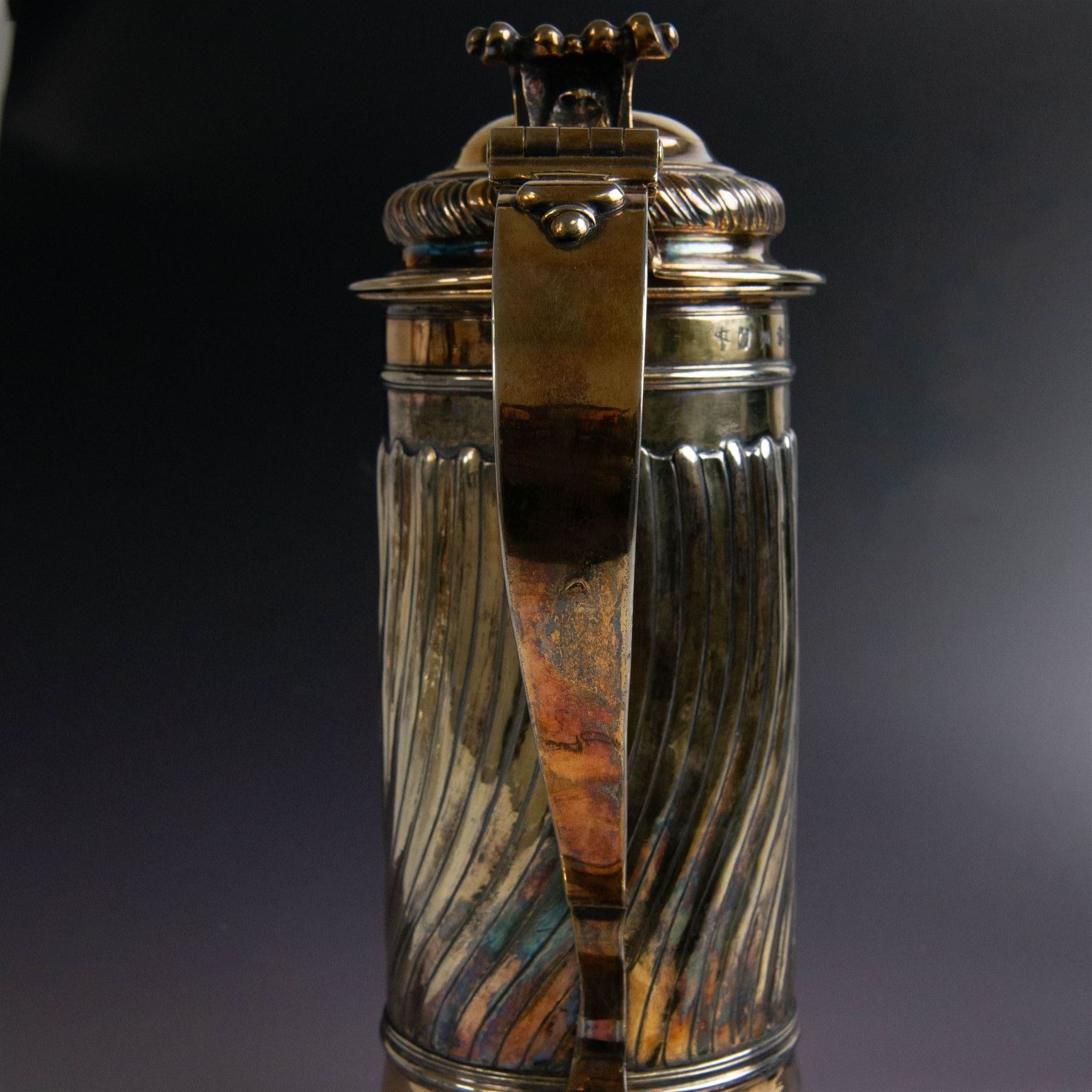 George I silver-gilt wine flagon, of tapering cylindrical form with part fluted body and upon circular spreading foot, with c-scroll handle, domed lid with rose to centre  and scroll thumb piece, hallmarked London 1725, maker's mark indistinct, with later refinements, the original hallmarks struck-through and re-assayed by the London Assay 2021, H33cm