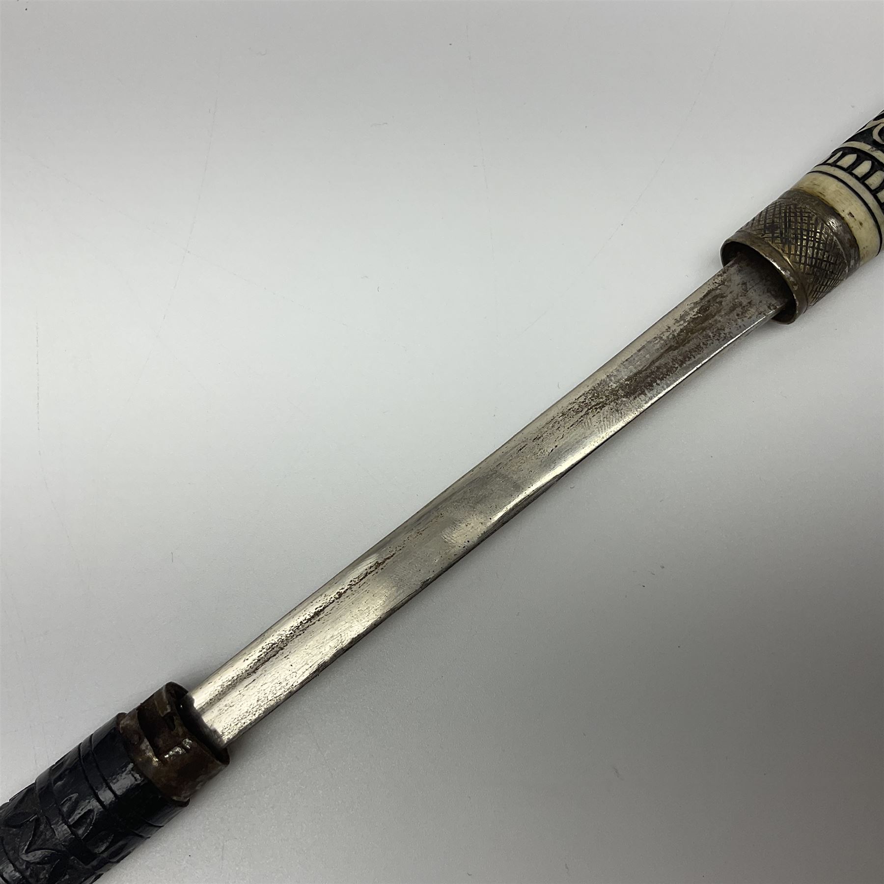 Early 20th century Indian ebonised wooden umbrella sword stick with 36cm blade, carved bone mount and black cloth cover L92cm overall; together with a similar Indian ebonised wooden sword stick with 64cm blade, carved bone mount and brass lion mask pommel L91cm (2)