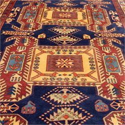 North West Persian Ardebil hand-knotted runner, indigo blue field composed of a repeating series of large stepped octagonal medallions enclosing a central hooked motif and stylized rosette, flanked by angular ivory and madder red latch hook devices, medallions linked by smaller geometric diamonds and serrated lozenges, guard borders with reciprocal motifs and main ivory border decorated with angular vines, with cotton fringe ends 