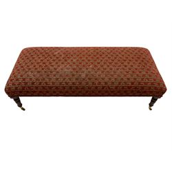 Rectangular beech framed footstool, upholstered in striped red fabric decorated with zodiac symbols, on turned supports terminating at brass castors