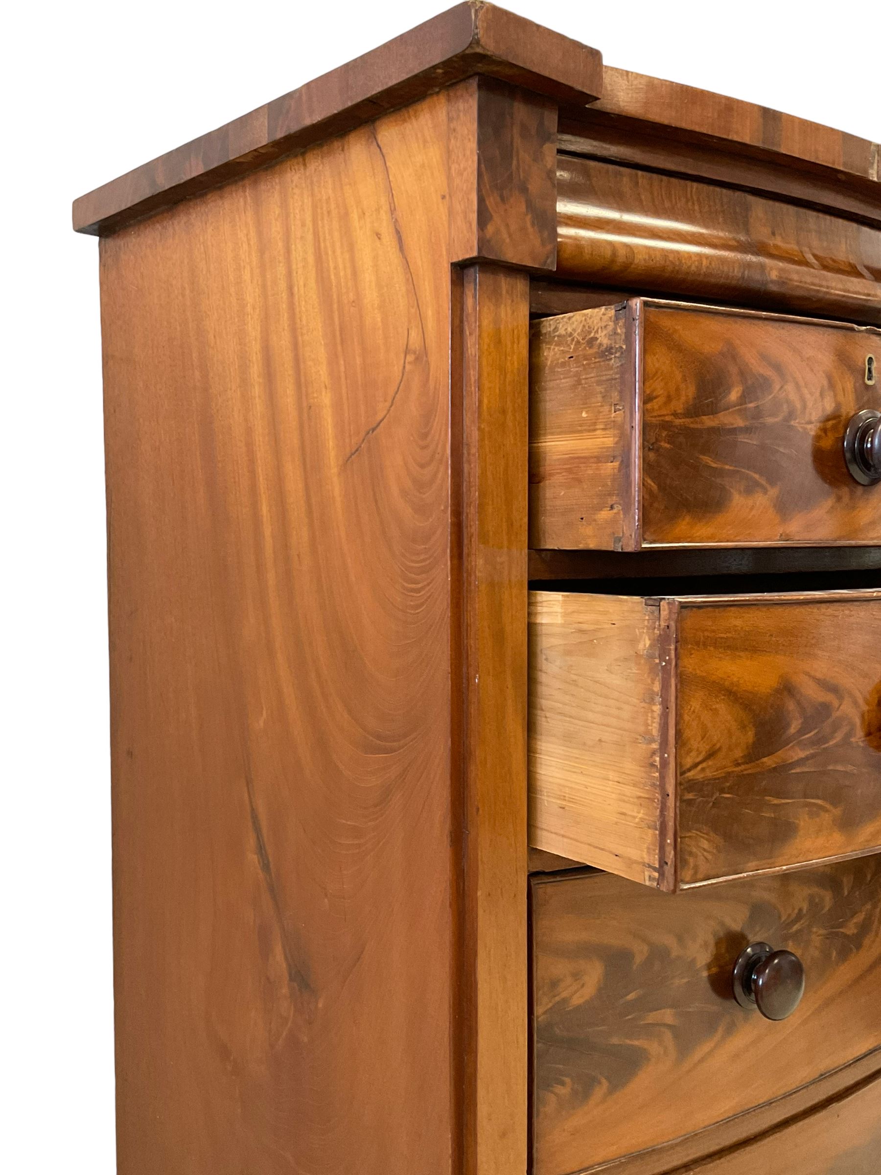Late 19th century mahogany bow-front chest, fitted with banded cushion drawer with secret catch, above two short over three long graduating drawers, each cock-beaded with turned handles, lower moulded edge over turned feet