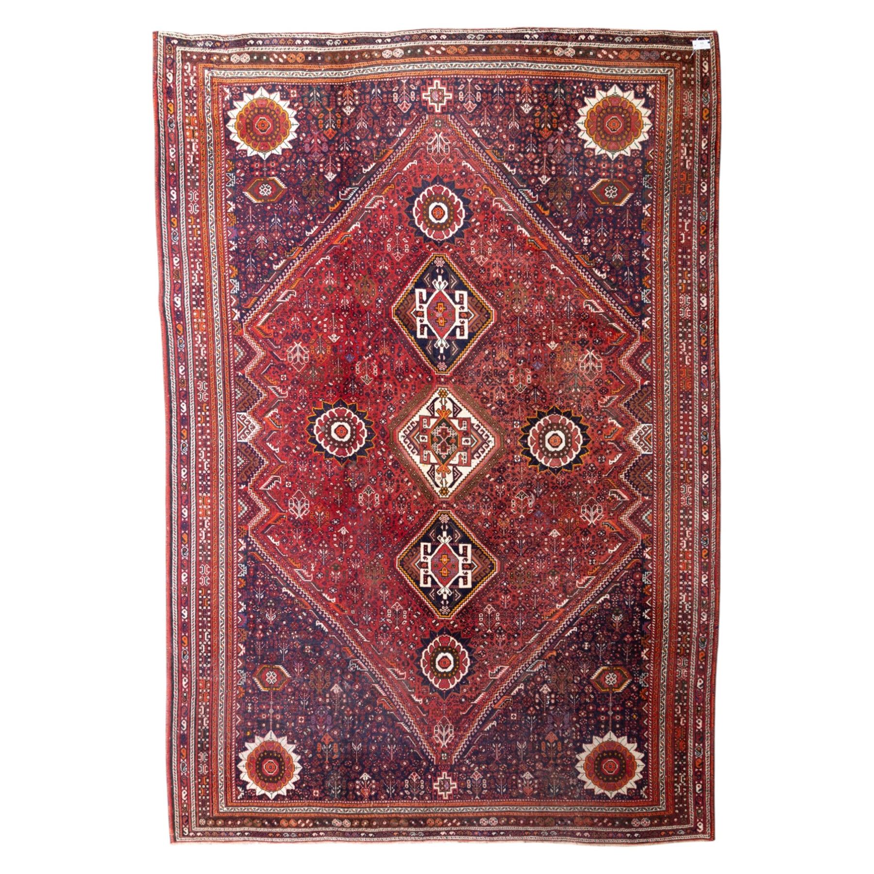 Qashqai wool carpet, red diamond-shaped field decorated with three stepped pole medallions, floral rosettes and scattered stylised motifs, within dark blue spandrels and multiple geometric guard borders