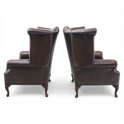 20th century Chesterfield style brown leather wingback armchairs, with button upholstered backs and wings, shaped scroll arms with studded borders, loose seat cushions, raised on cabriole supports with pad feet
