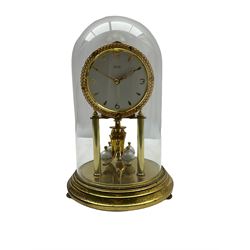 A 20th century Kundo Anniversary 400 Day clock, made by German manufacturer Kieninger & Obergfell, with a gilt brass base and four ball rotary pendulum, white painted dial with gilt three-hour Arabic numerals and batons, with pierced brass hands, open bezel with gilt ropework design, under a glass dome.
No Key. 
