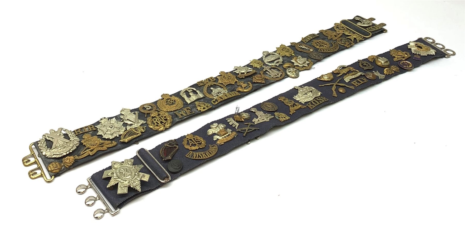 Collection of Glengarry and cap badges, shoulder titles, collar dogs, buttons etc mounted on two military belts, including rare Kitchener's Army Volunteer Training Corps Surrey 1915, two Ulster Volunteer Force (L6521 & L2007), Royal Irish, North Irish Horse, Inniskillings, Royal Irish Rifles, London Irish, London Irish Rifles, Royal Irish Fusiliers, Queen's Own Cameron Highlanders, Royal Scots, 9th Battalion (Glasgow) HLI, Royal Welch Fusiliers, South Wales Borderers, Church Lads Brigade, various regiments and corps, RUC and officer's training corps buttons etc
