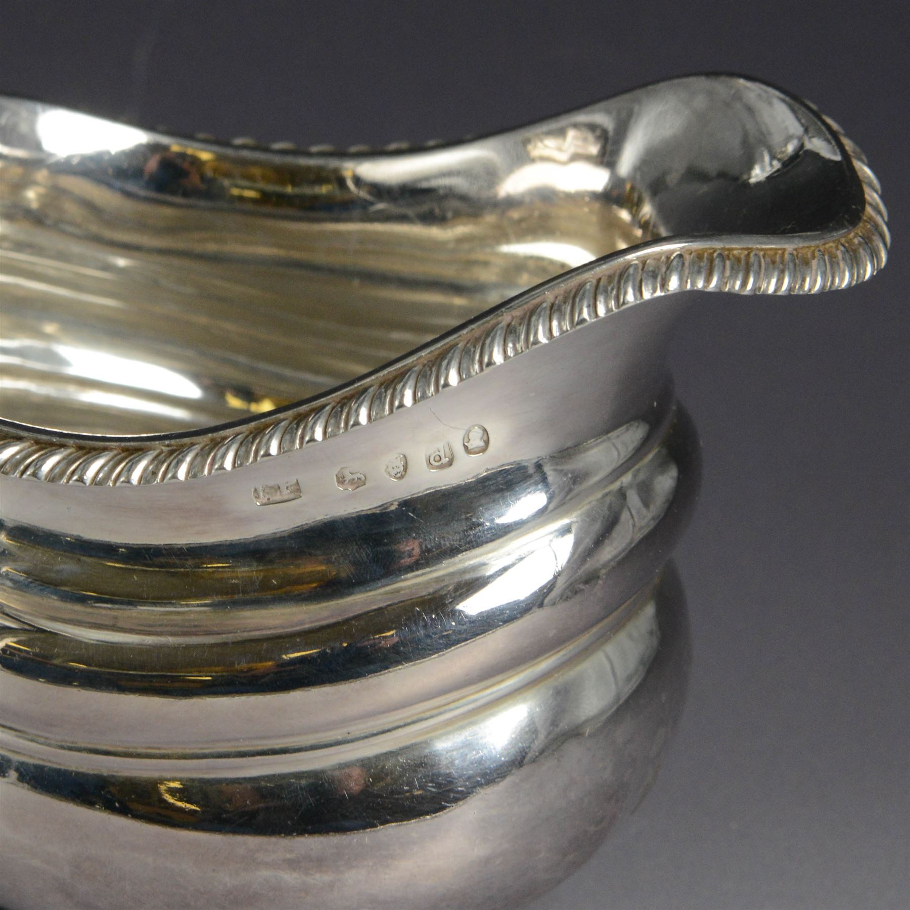 George III silver milk jug, of oval form with oblique gadrooned rim and acanthus leaf capped handle, upon four bun feet, hallmarked London 1819, maker's mark worn and indistinct, H10cm