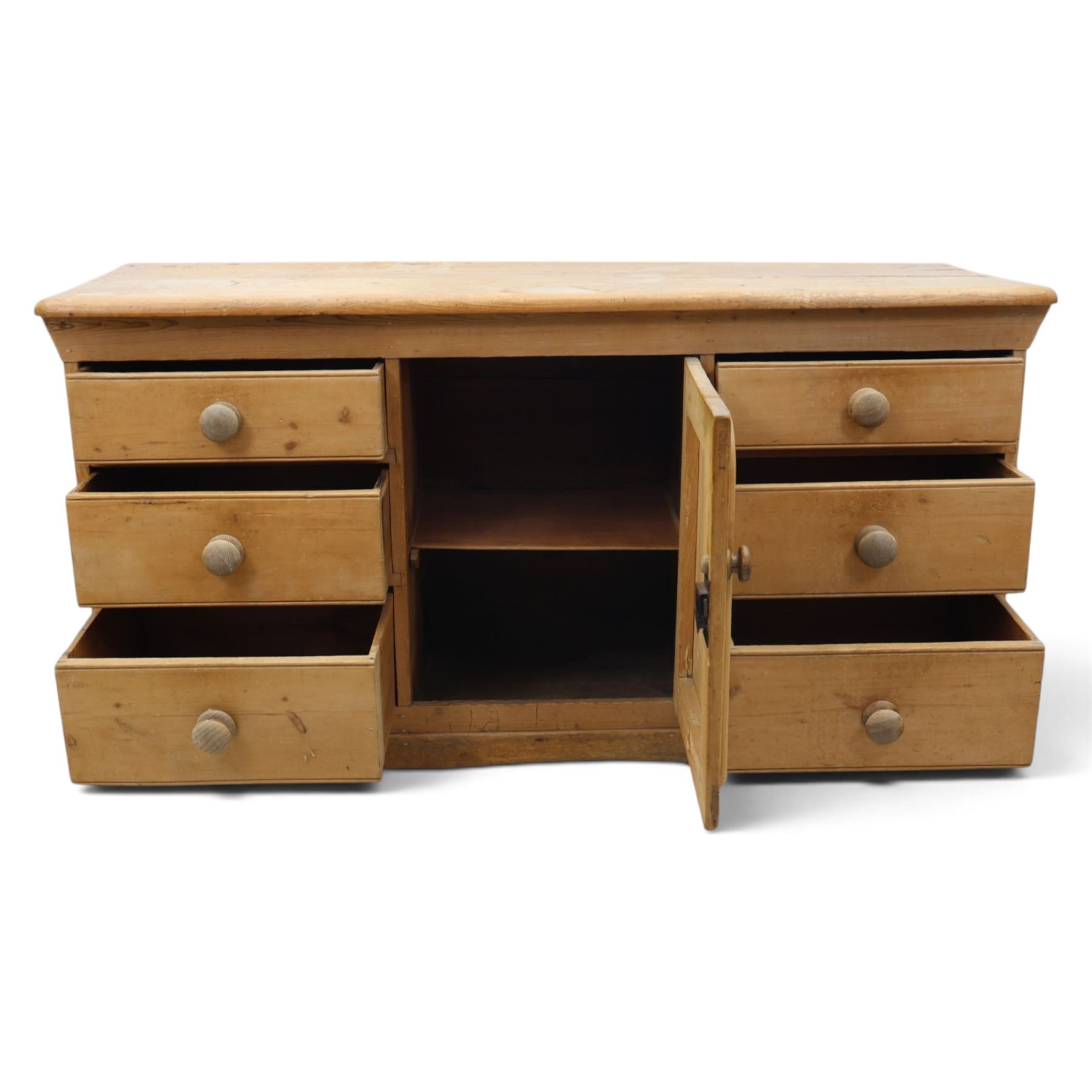 Victorian stripped pine sideboard, rectangular plank top rounded edges, with central cupboard door with shaped panel, flanked by two banks of three graduating drawers with turned knobs, raised on a plinth base 