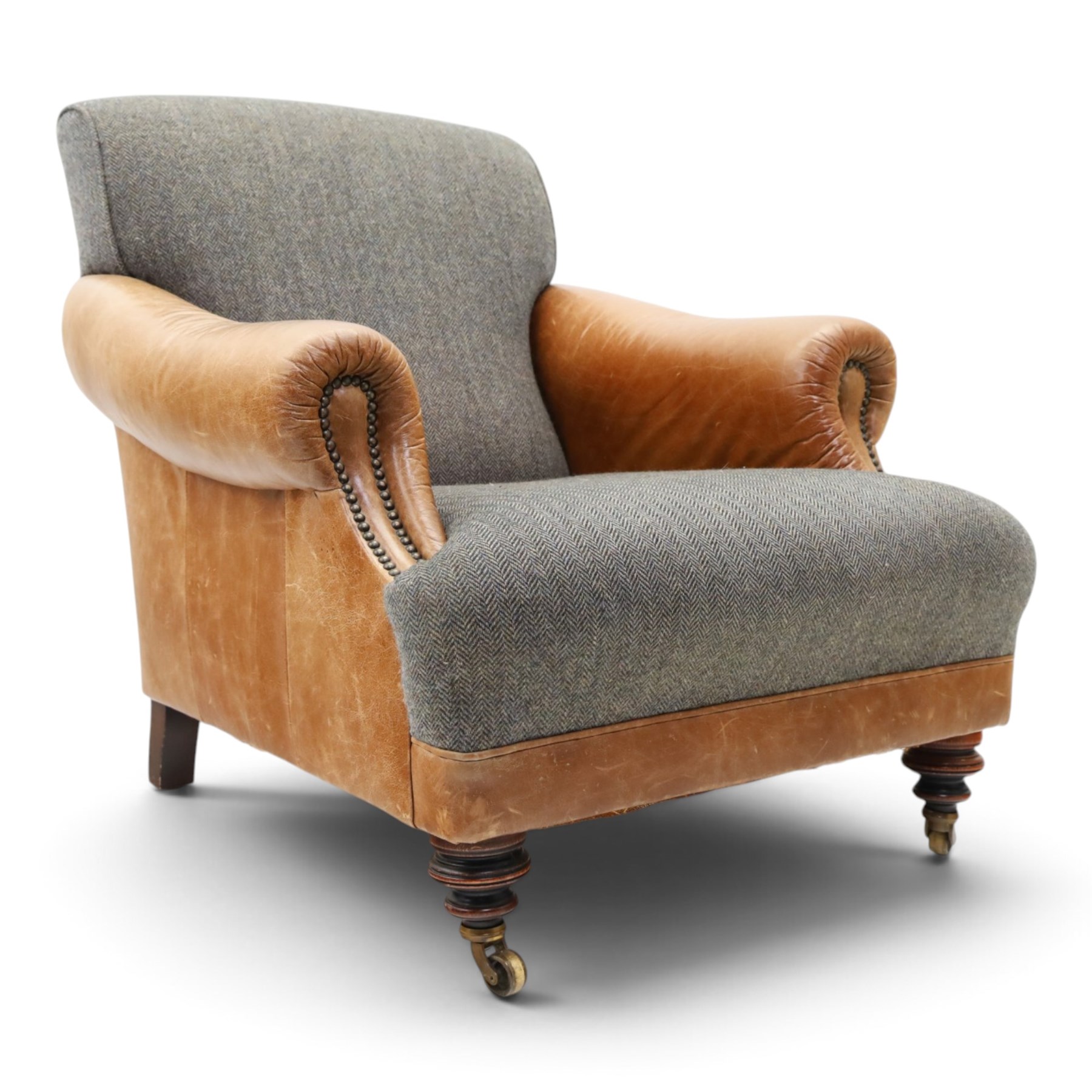 Tetrad - 'Taransay' Harris Tweed and tan leather club armchair, Howard shape with reclined back over deep seat and rolled arms with studwork, raised on turned front supports with castors, the sides and arms upholstered in tan leather with seat and back in herringbone-stitched Harris Tweed