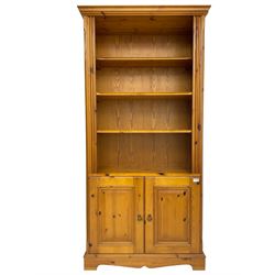 Traditional pine open bookcase on cupboard, fitted with three adjustable shelves over a double cupboard with panelled doors