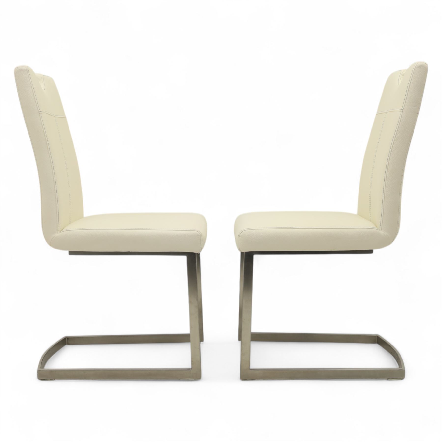 Set of seven contemporary style dining chairs, each with a high padded back and seat upholstered in faux leather on brushed steel sled bases  