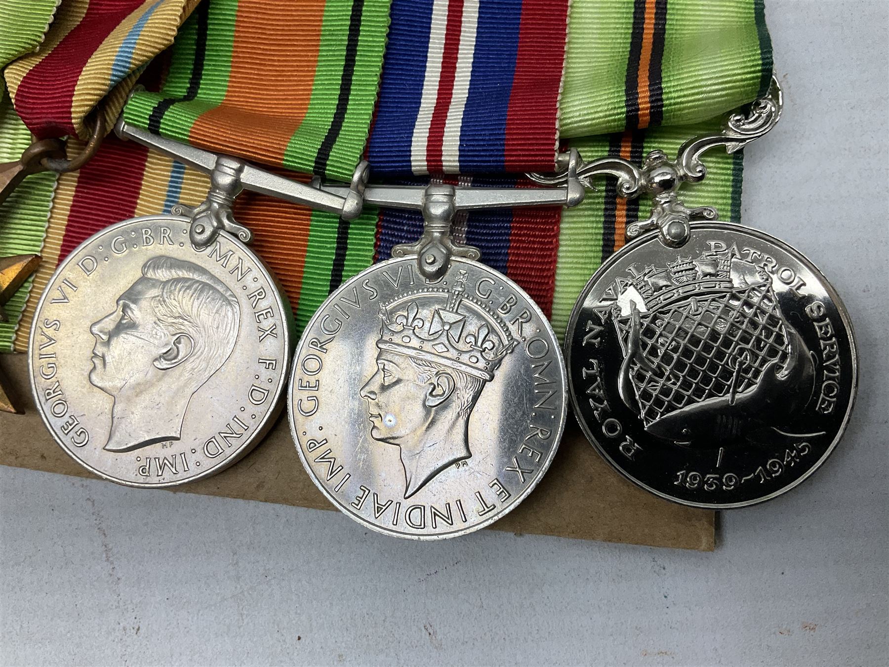 WW2 Royal Naval group of eight medals comprising OBE, hallmarked silver Distinguished Service Cross inscribed verso Lieut. J.R. McCluskie RNVR 1945, 1939-1945 Star, Atlantic Star, Africa Star, 1939-1945 War Medal, Defence Medal and Royal Naval Patrol Service Medal inscribed Lieutenant J.R. McCluskie Royal Naval Patrol Service; with seven original photographs of a sea battle 27th November 1940 against the Italian Fleet and another photographic postcard of Sir Stafford Cripps arriving on board one of the vessels.