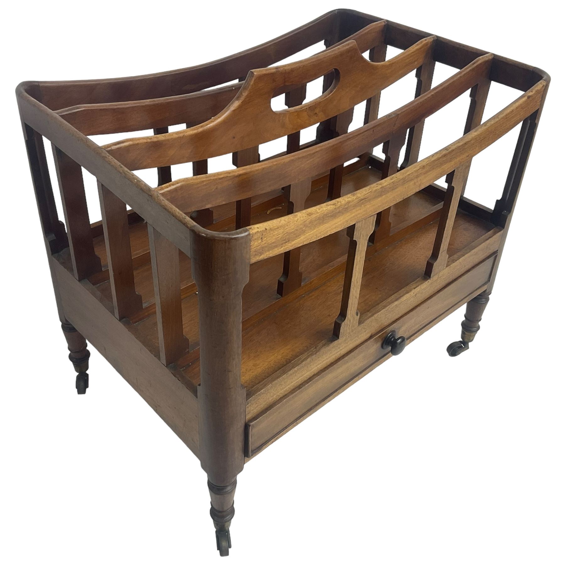 George III mahogany four-division Canterbury, the concave shaped dividers with a central pierced handle, over a single cock-beaded drawer, raised on turned supports terminating in brass cups and castors