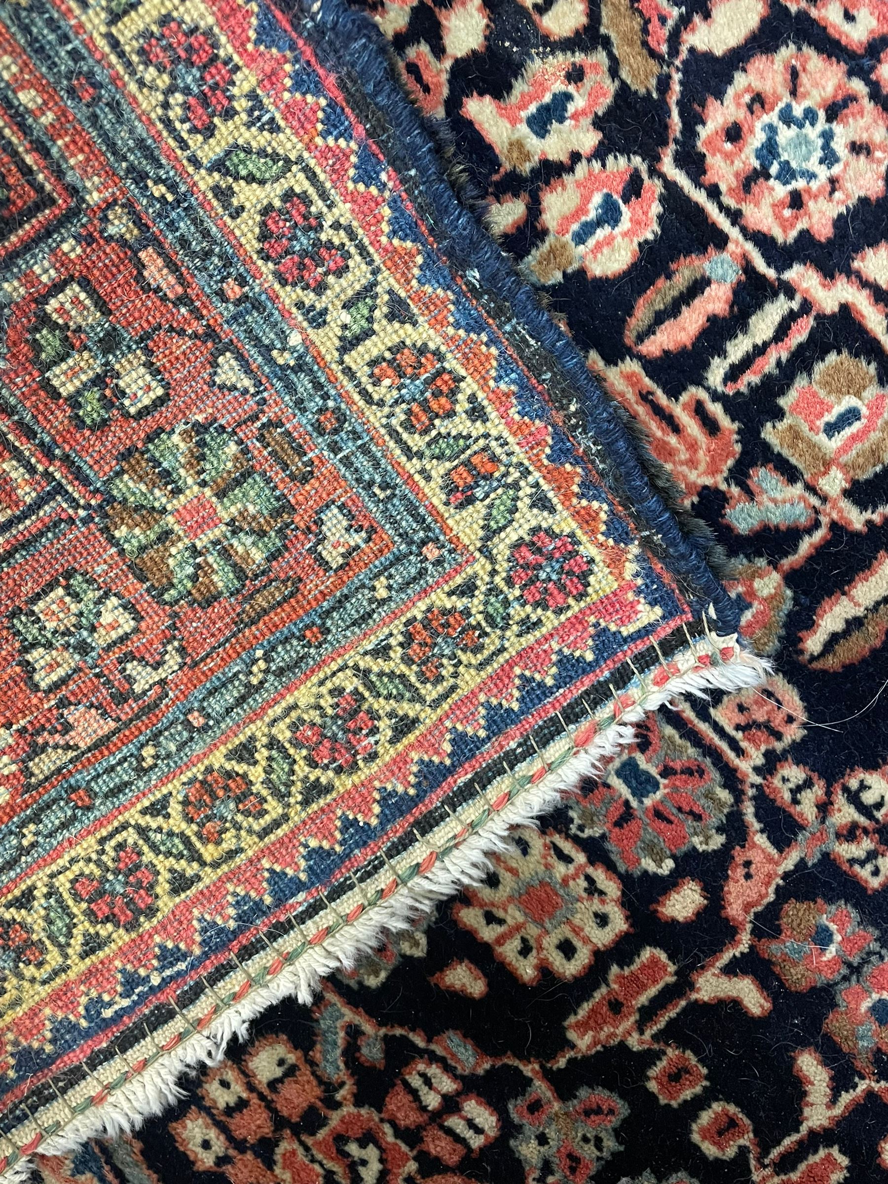 Persian indigo ground rug, the field decorated with intricate interlaced foliage branches and small flower heads, shaped floral design central medallion, the border decorated with scrolling branch and flower heads within guard bands 