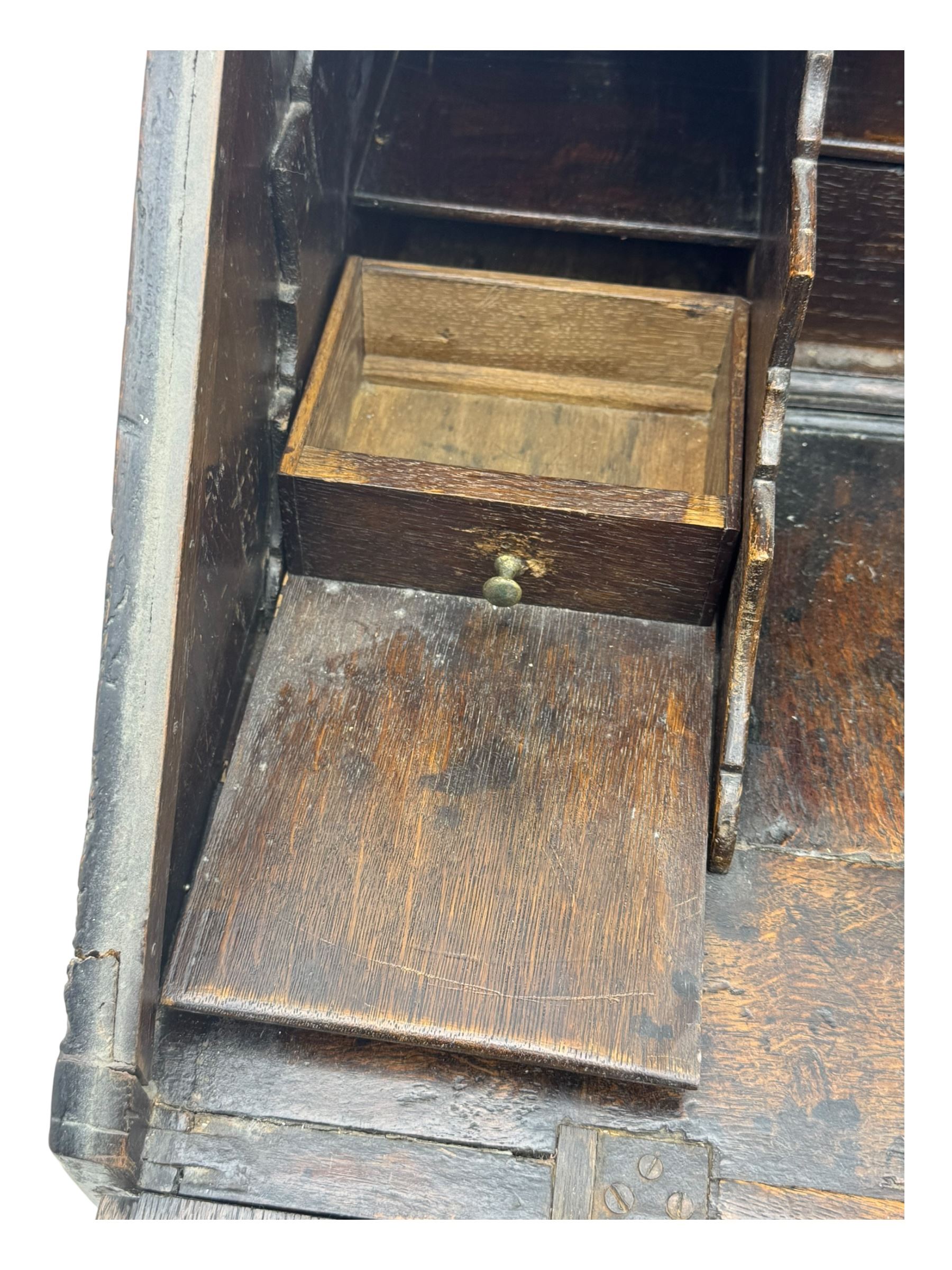 George III oak bureau, sloped fall-front enclosing a fitted interior with pigeonholes, small drawers, and a central compartment, over two short and two long drawers, brass escutcheons and drop handles, raised on bun feet