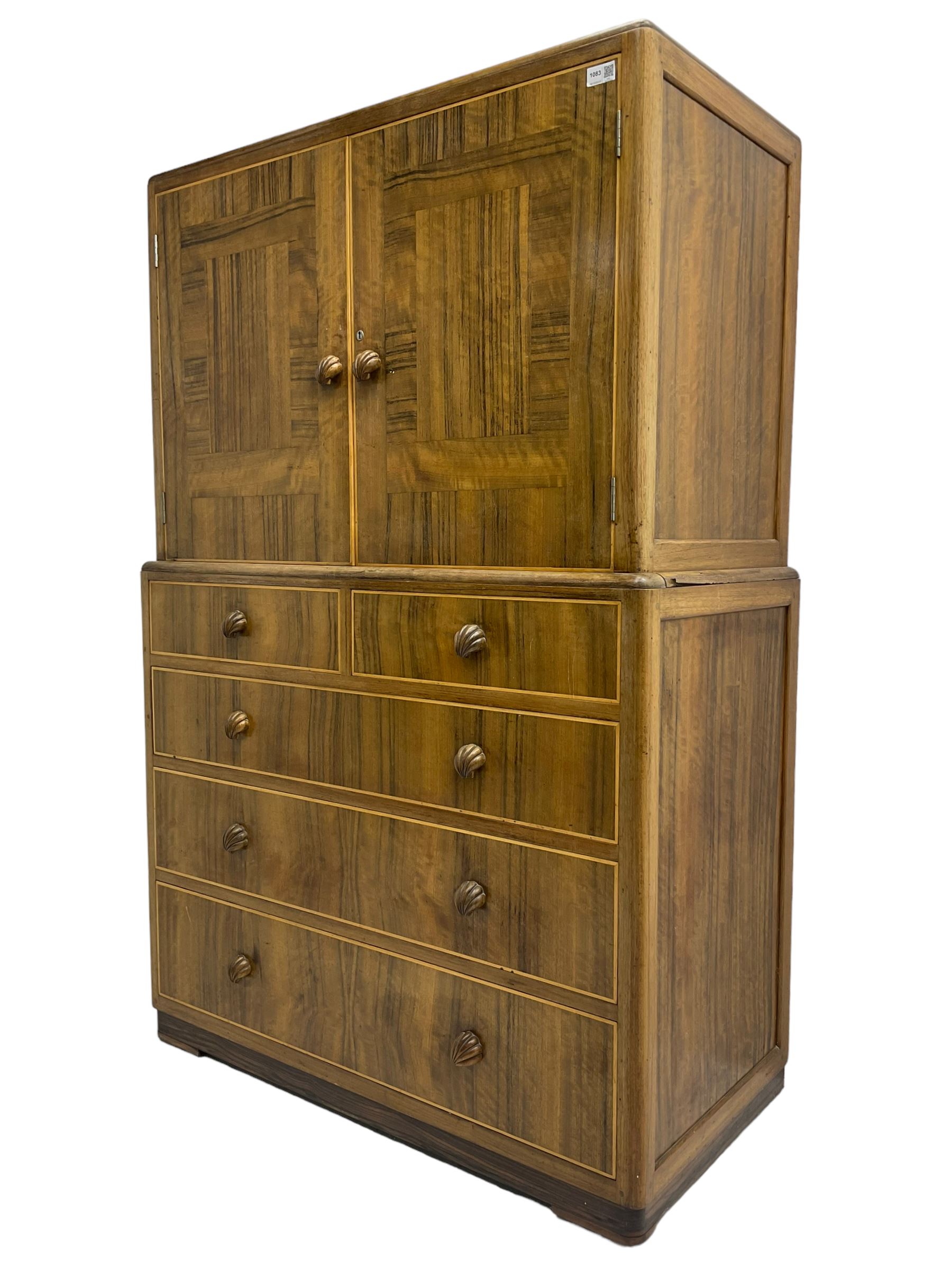 Early 20th century Art Deco walnut cocktail tallboy chest, fitted with double cupboard enclosing two shelves over two short and three long drawers, each with shell shaped handes