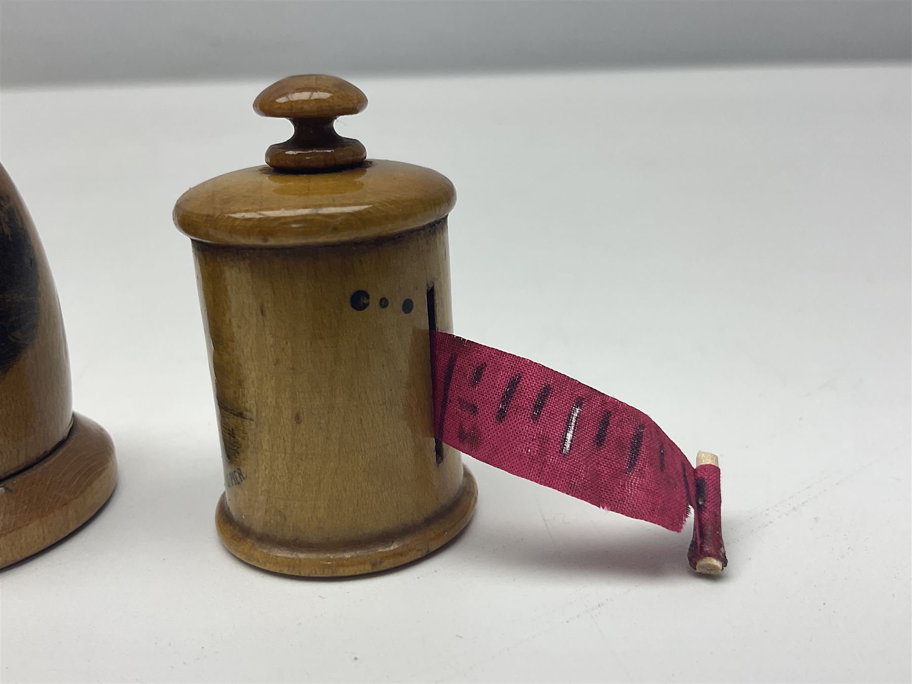 Six sewing related Mauchline ware comprising an oval reel box with internal label for Clark & Co's, tape measure, pin case and three thimble holders of ovoid form 