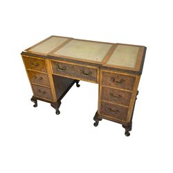 Early to mid-20th century walnut writing desk, inset leather top with foliate carved edge, fitted with seven drawers with brass handles, on shell carved cabriole feet