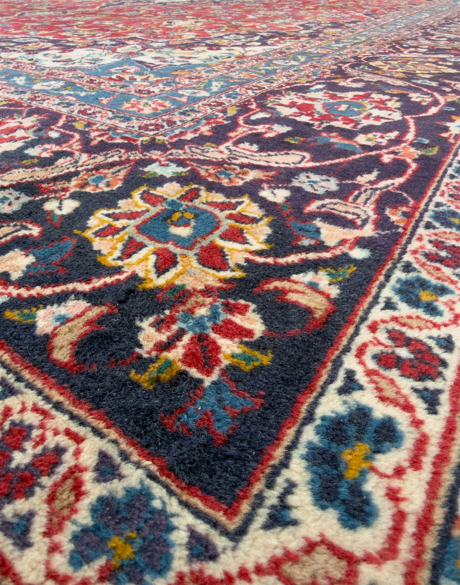 Pair of Persian wool rugs, each with rich red ground, one centred with a diamond-shaped medallion and navy spandrels within a floral field, the other with radiating floral medallion and scrolling foliate motifs, both enclosed by multiple borders with palmette and flowerhead designs, from the region of Kashan 291x376, 299 x 378 