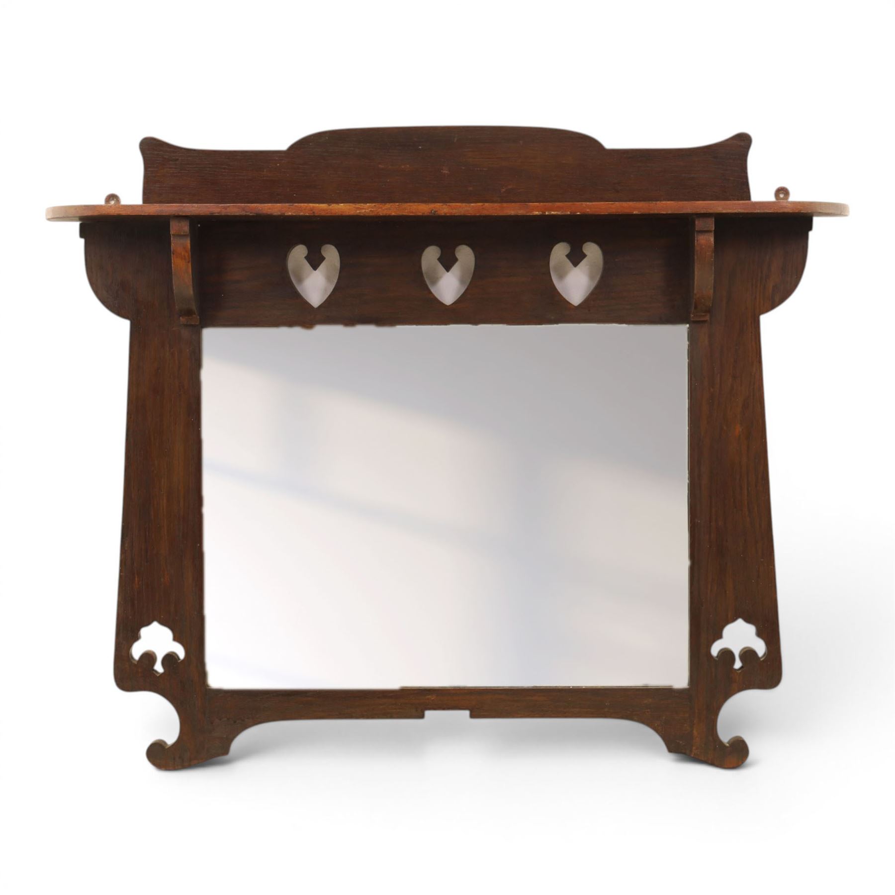 Arts and Crafts oak wall mirror, rectangular mirror plate within shaped frame, raised shelf with shaped back and pierced heart detail, bracket supports and shaped lower rail