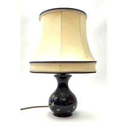 A Moorcroft table lamp, of baluster form, decorated in the Anemone pattern upon a dark blue ground, with impressed marks beneath, with accompanying cream shade with piped detail, overall H38.5cm.