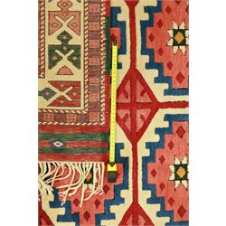 Anatolian Soumak rug, ivory ground decorated with a grid of eight octagonal medallions in terracotta red outlined in blue, centered with a star motif in vertical rows, framed by a series of geometric borders in ivory, green, and blue, incorporating hooked devices and stylized lozenges and stripped end panels, with signature at either end 