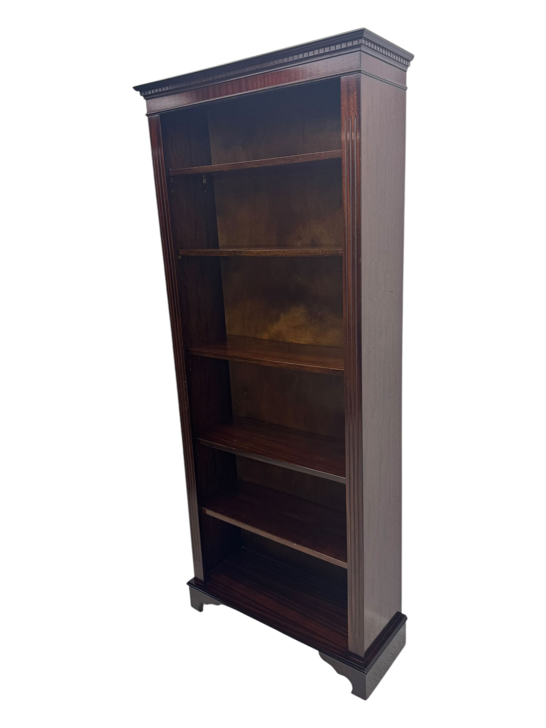 Early 20th century mahogany open bookcase, the rectangular top with dentil moulding, the sides with fluted decoration, fitted with five adjustable shelves, on ogee-moulded bracket supports