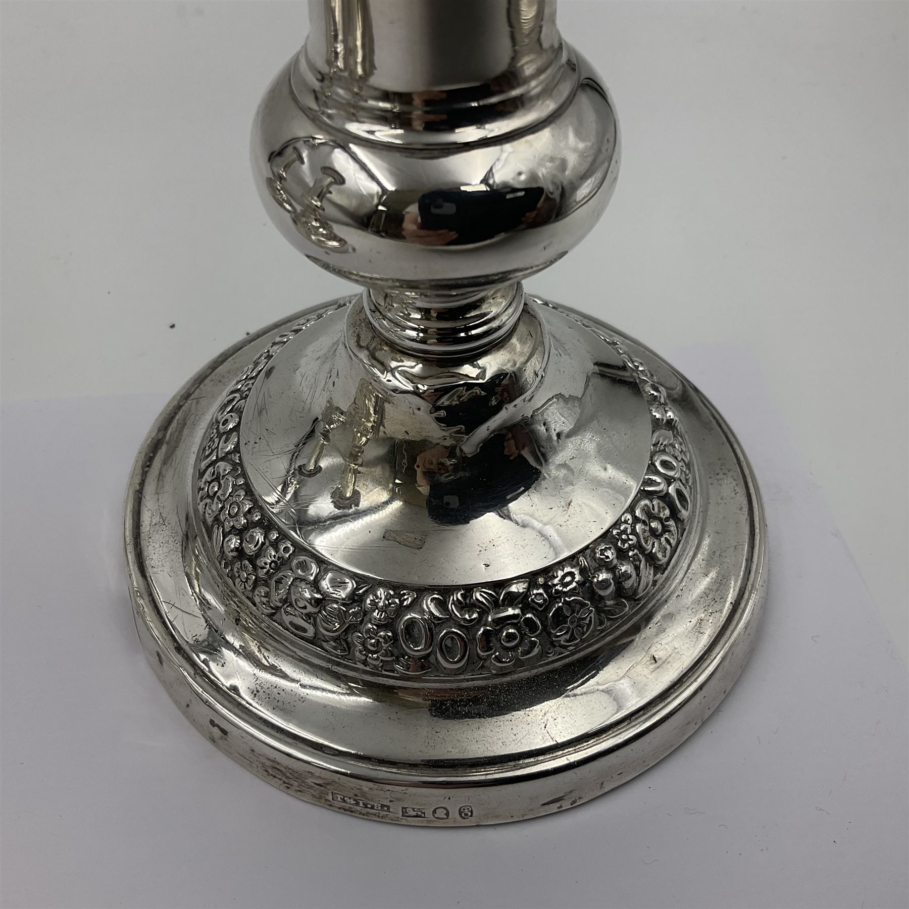 Four George III silver candlesticks, each upon knopped stem and weighted circular stepped foot, the foot and removable sconce repousse decorated with a band of flower heads, hallmarked to sconce and foot Thomas & John Settle, Sheffield 1820, H17.5cm