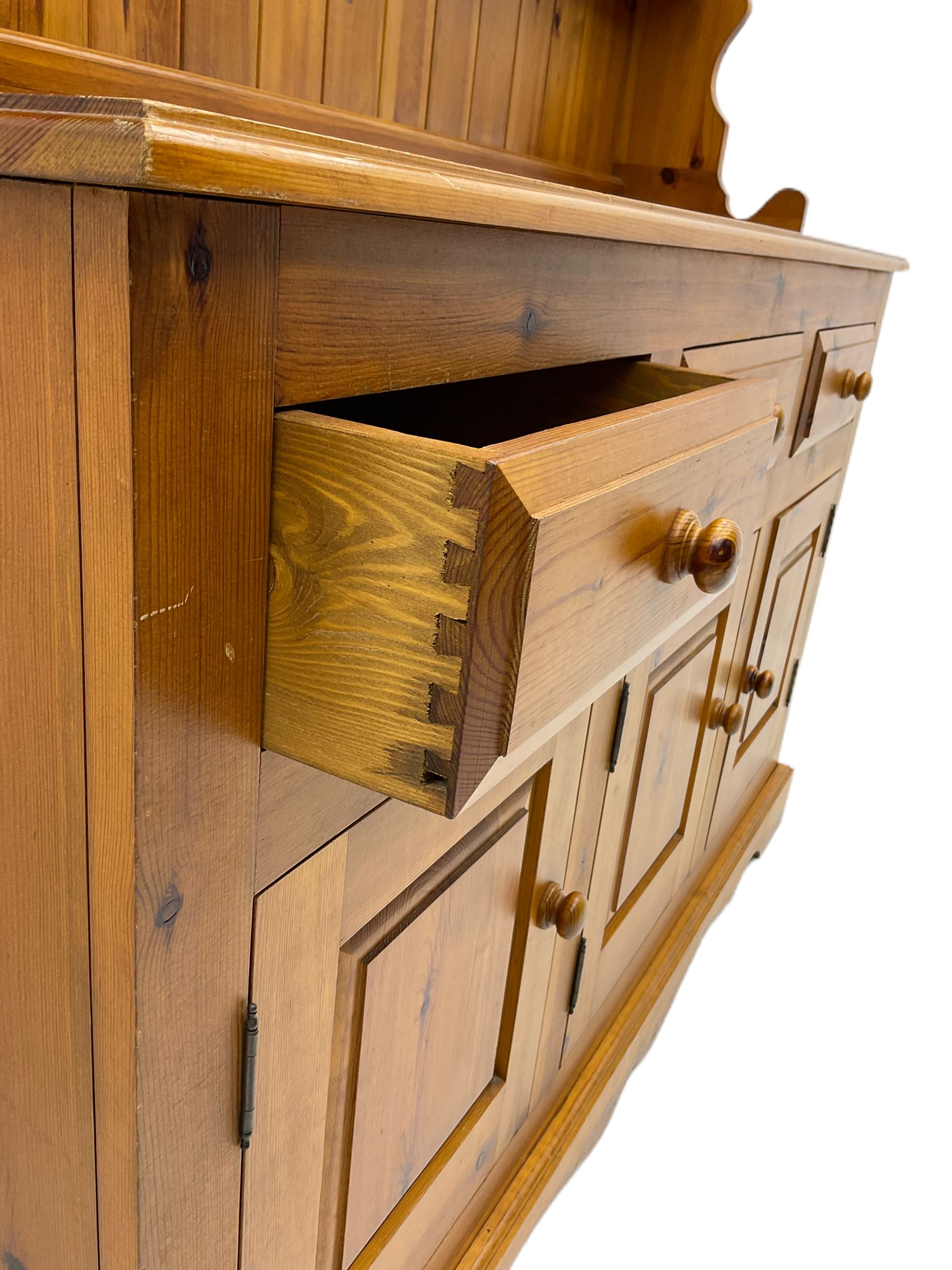 Pine farmhouse dresser with three drawers and three cupboards, and two tier plate rack