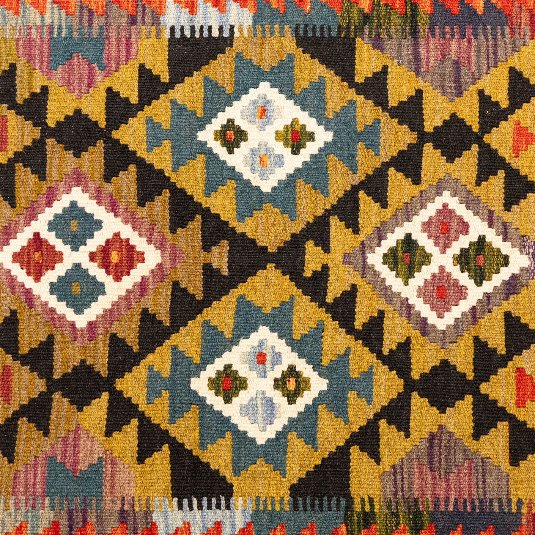Afghan Maimana flatweave kilim runner, central field features large bold nested diamond motifs and stylized geometric lozenge patterns on olive purple, blue, and green tone ground, border stripe in orange ground, and fringe
