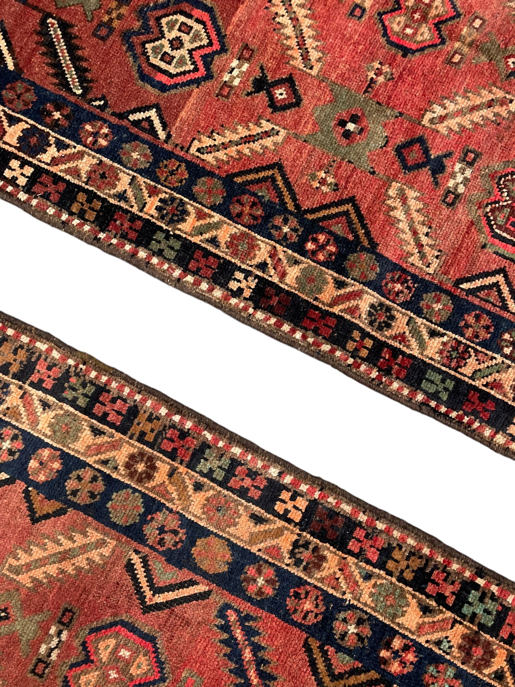 Near pair of Persian Azerbaijan red ground runners, each rug decorated with Nazarlik and stylised leaf motifs, enclosed with three band border decorated with flower heads and geometric motifs 

406cm x 99cm 
409cm x 102cm
