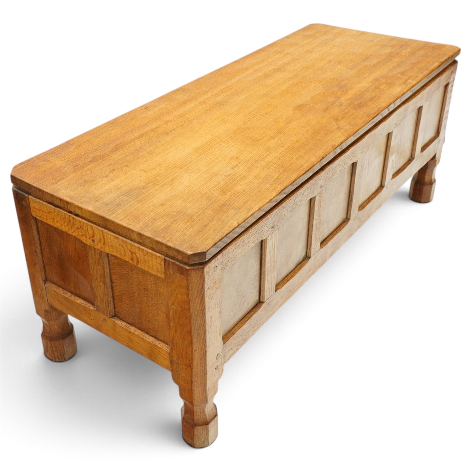 Mouseman - 1950s adzed oak blanket chest of unusual proportions, the rectangular hinged top with canted corners, over a sextuple panelled front, raised on turned octagonal feet, carved with mouse signature, by the workshop of Robert Thompson of Kilburn