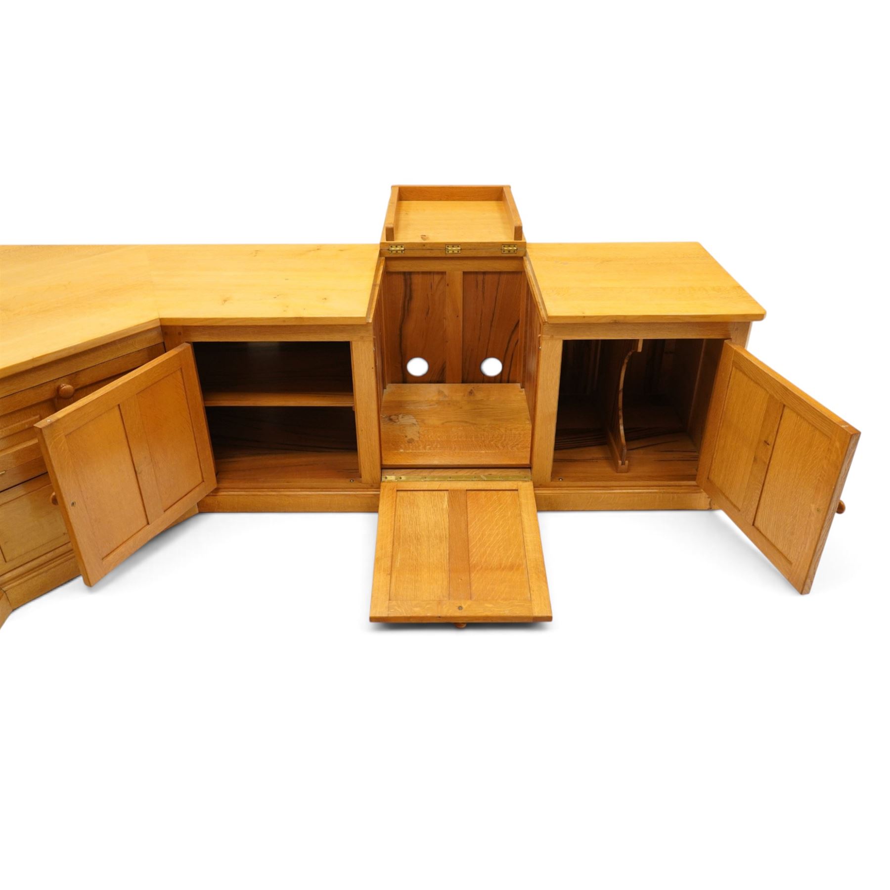 Seahorseman by Shaw & Riley - bespoke large Yorkshire oak corner sideboard or media unit, of L-shape form, with three cupboard doors, a fall front drawer over a regular drawer, a lift up panel for a record player, multiple apertures for wires, raised on a plinth base, with signature Seahorse carving from the workshop of A. Shaw & Riley Ltd, Hessay