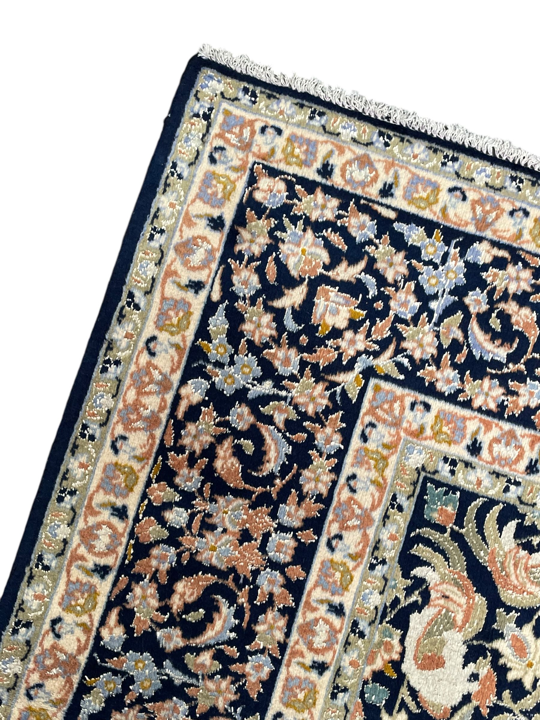 Persian Kashan indigo ground rug, the field consisting of trailing flower head bands and leafy branches, decorated with kuş or bird motifs, the border with repeating border containing curling leaves and flower heads, within guard bands 