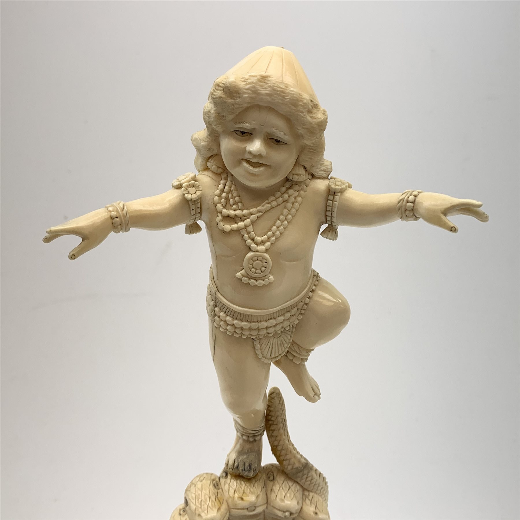 A large Japanese carved ivory okimono, modelled as a figure stood upon one leg with arms outstretched, upon a five headed serpent emerging from waves, H30cm.