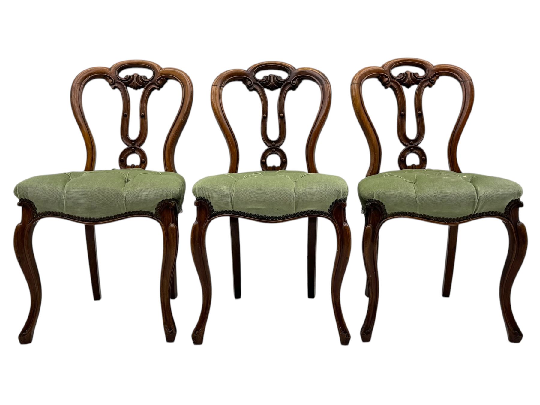Set of six carved Victorian walnut balloon back dining chairs, button upholstered in green velvet fabric, back with foliate carved decoration supported on scroll form legs 
