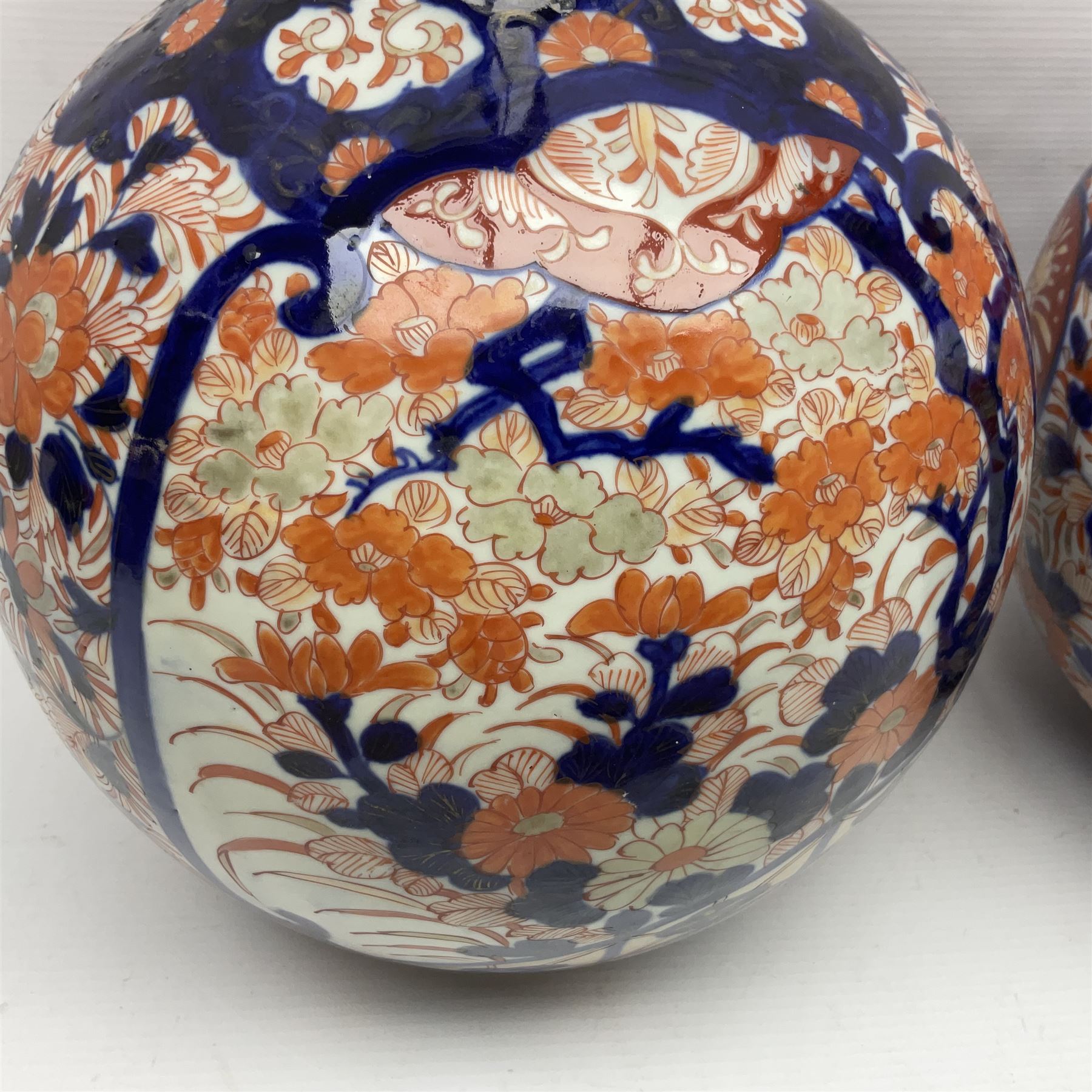 Pair of large 19th century Japanese Imari porcelain bottle vases, painted with shaped reserves of peonies, chrysanthemums and prunus blossom, each H46cm