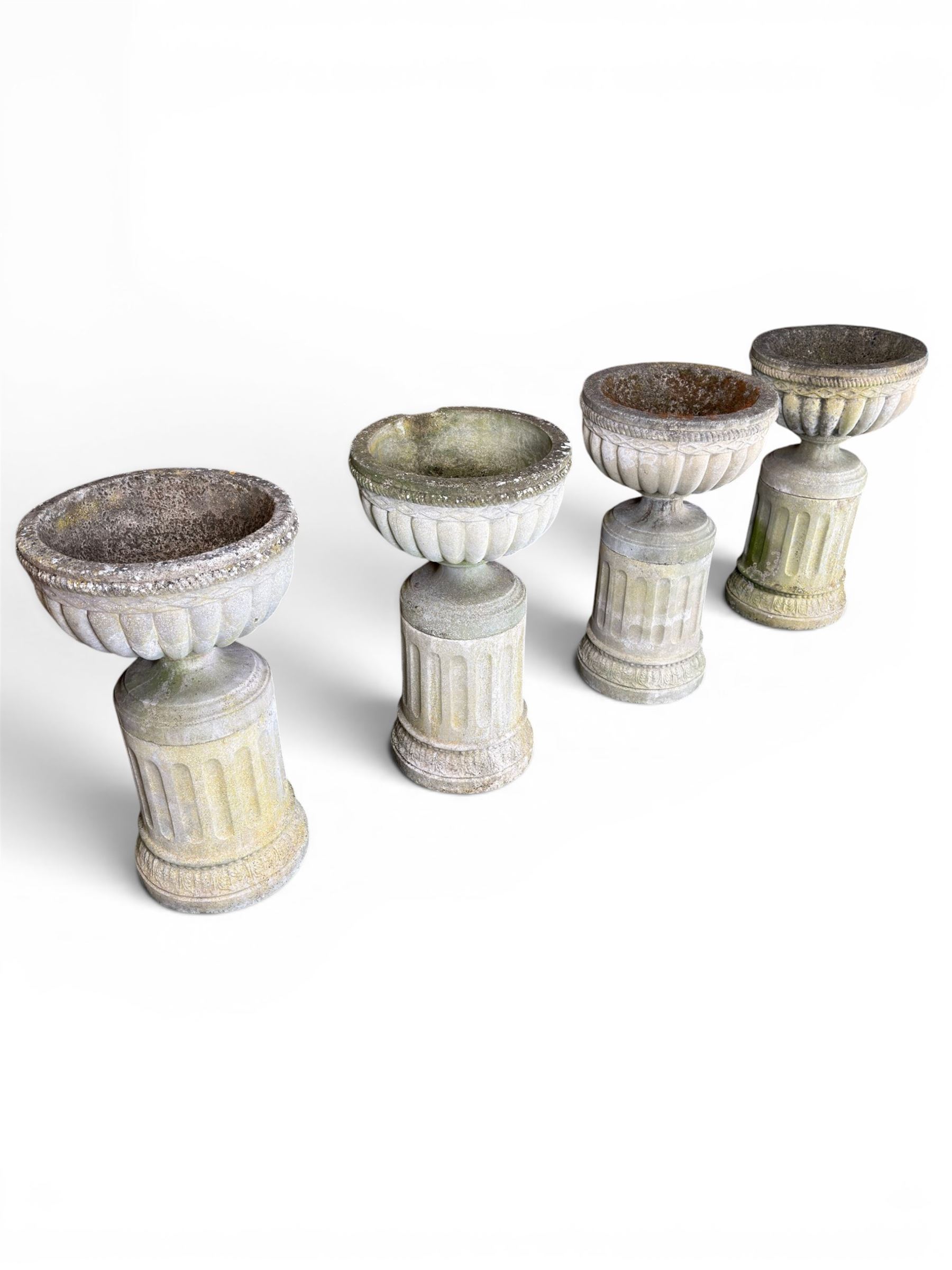 Four 20th century good quality weathered cast stone pedestal urns, circular lobed bowls with rope twist and lattice border, raised on squat base with fluted columns