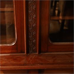 Victorian carved mahogany enclosed bookcase on cupboard, projecting moulded cornice over twin glazed doors enclosing adjustable shelves, flanked by foliate carved uprights, the lower section fitted with two cushion moulded drawers over twin panelled cupboard doors, divided and flanked by conforming carved uprights, on plinth base