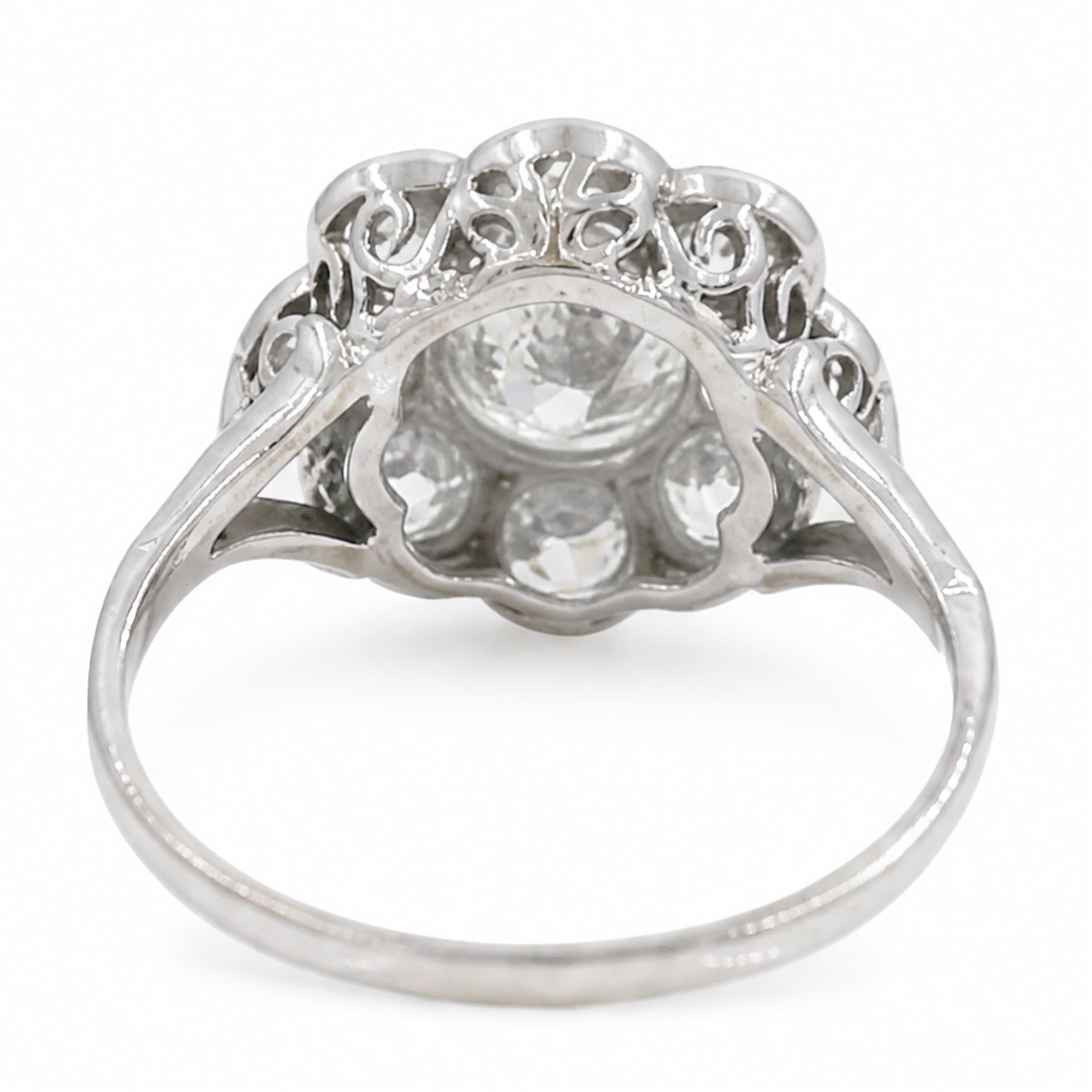 Early 20th century platinum diamond daisy flower head cluster ring, principal round cut diamond of approx 0.65 carat, surrounded by eight milgrain set old cut diamonds, within a pierced scroll design gallery, total diamond weight approx 2.15 carat